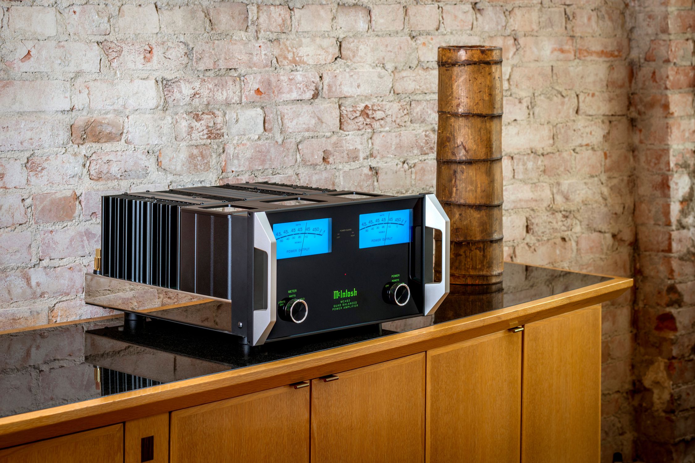 mcintosh MC255 amplifier over a wood dresser with a stone wall in the back