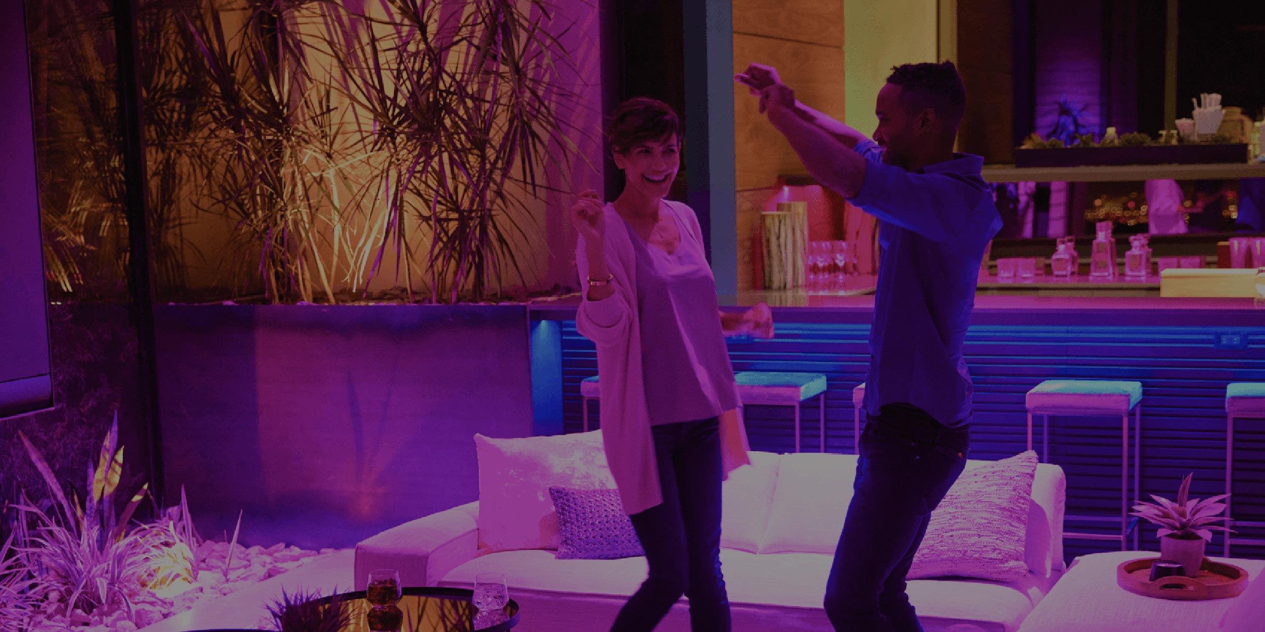 Couple dancing in a lounge with colorful lighting and modern decor