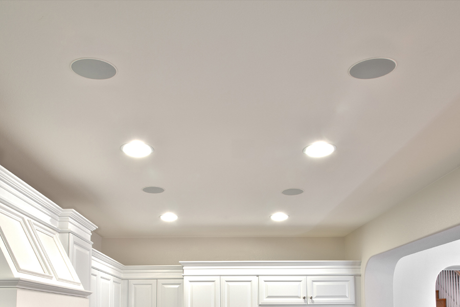 Kitchen ceiling with Sonance in-ceiling speakers and recessed lighting, providing a clean and functional design.