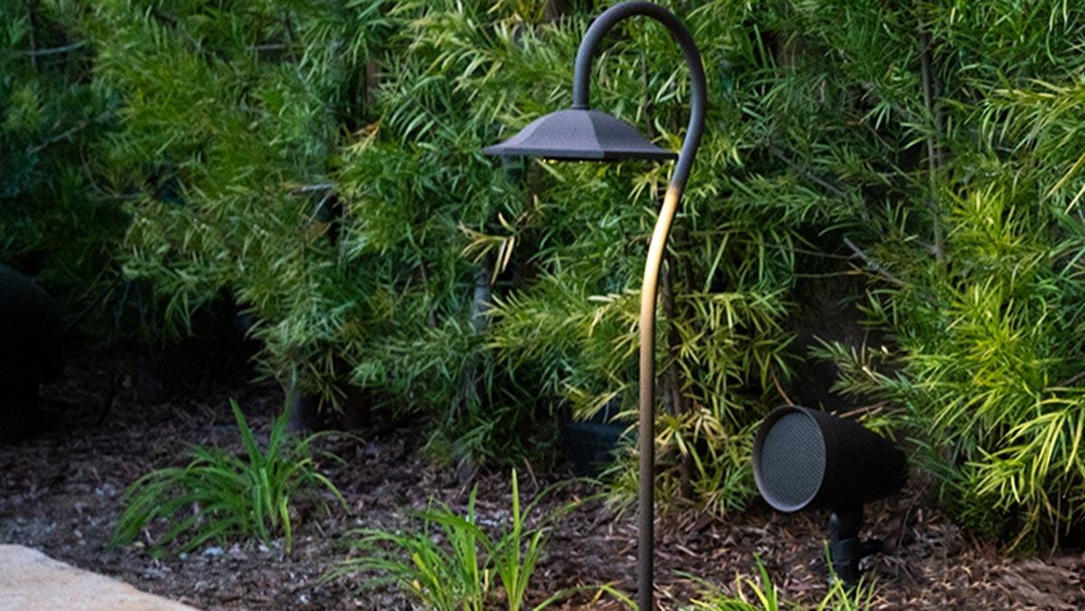Sonance landscape lighting and speakers seamlessly integrated into a lush garden with dense foliage.