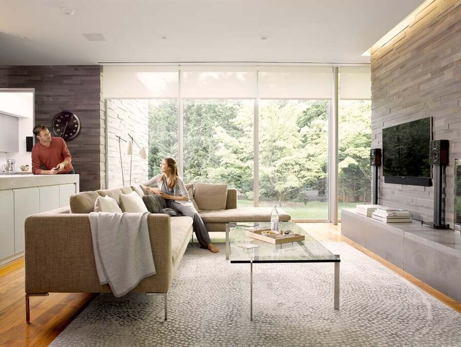 A couple chats while sitting in their luxury Savant home with a view of their outdoor spaces.