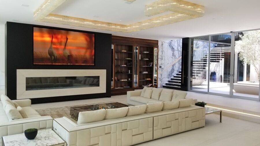 An elegant and luxurious living room with a wide screen displaying nature scenes.
