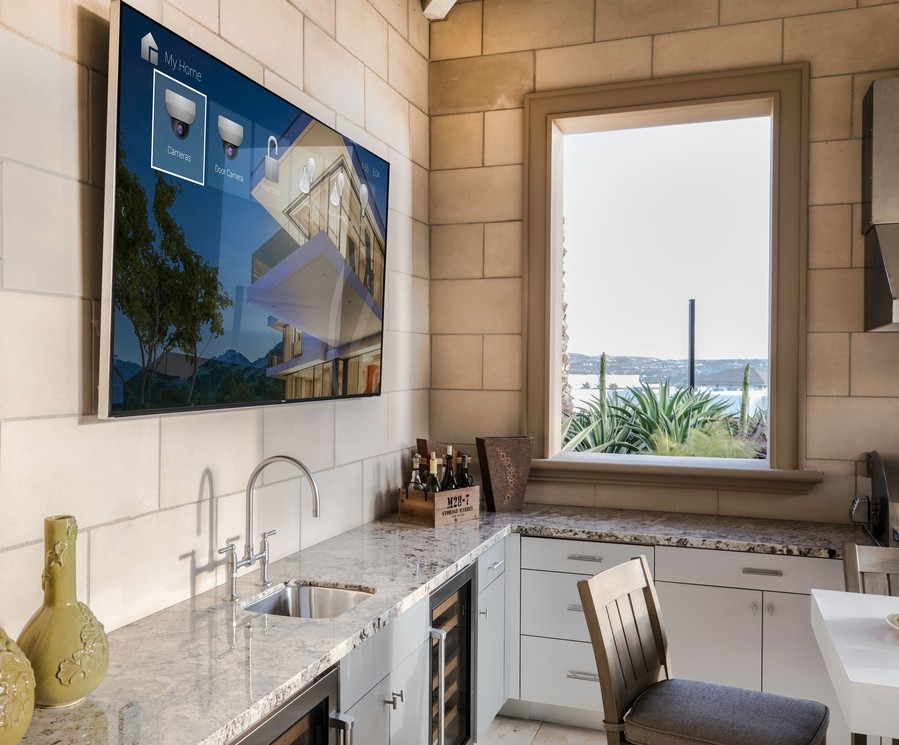 An elegant kitchen with a TV displaying the Control4 interface.