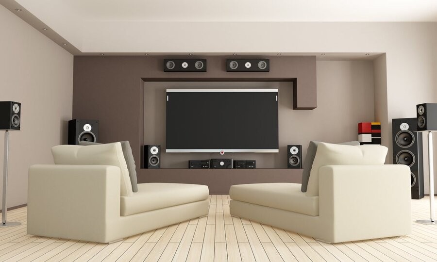 A media room setup featuring two seats, a mounted TV screen, and surround sound speakers in place.