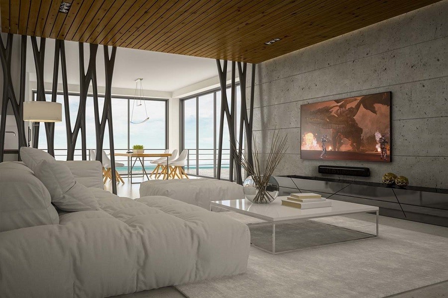 Living room with ultra-modern decor, white couches looking over ocean view, and high tech media system at the center.  