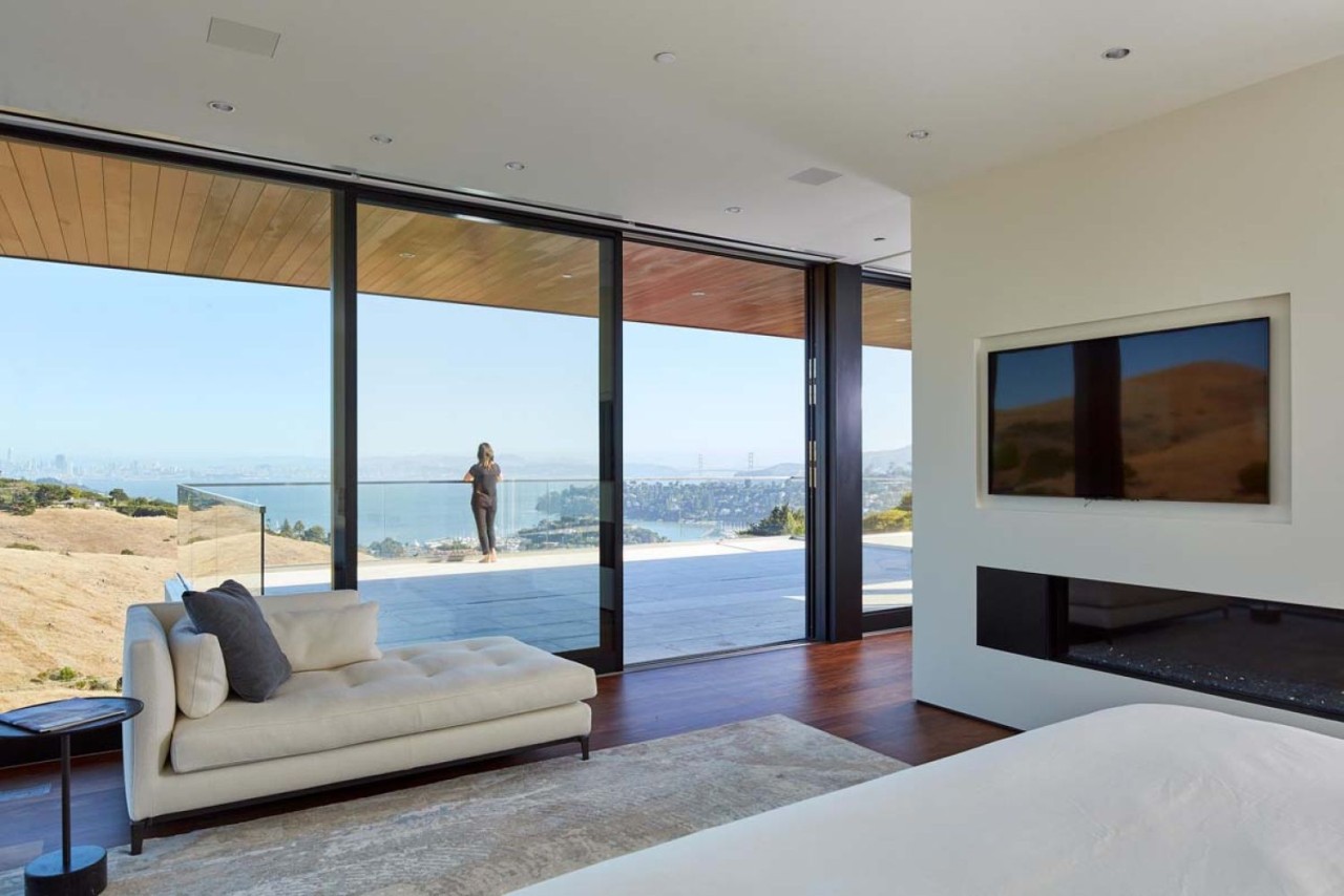 Sophisticated and modern living room with glass wall to and deck with the city of San Francisco in the background.