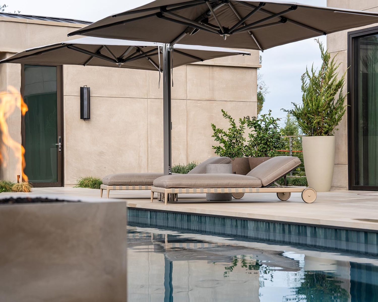 Poolside loungers under umbrellas beside a modern home