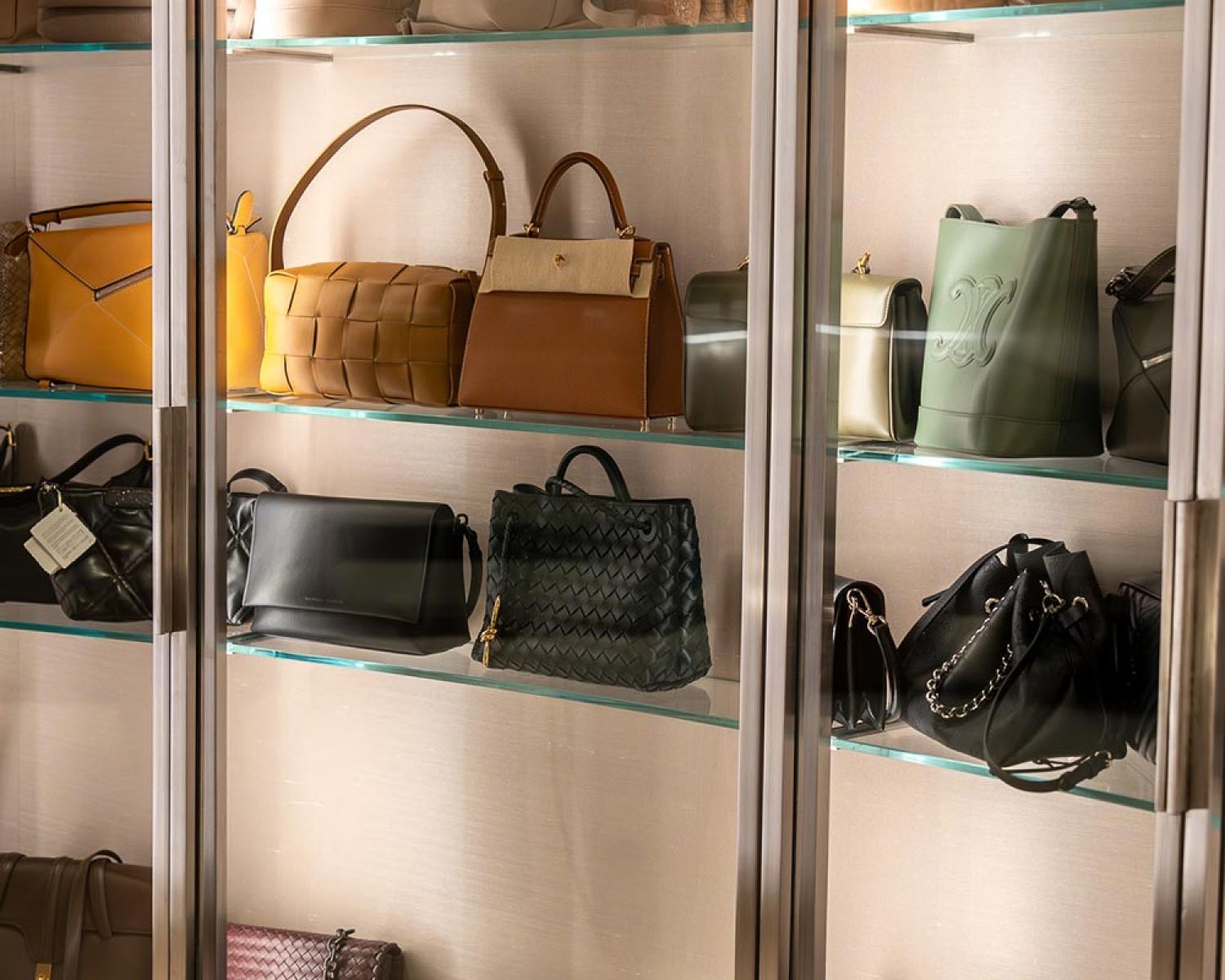 Glass display shelves showcasing designer handbags in a walk in closet