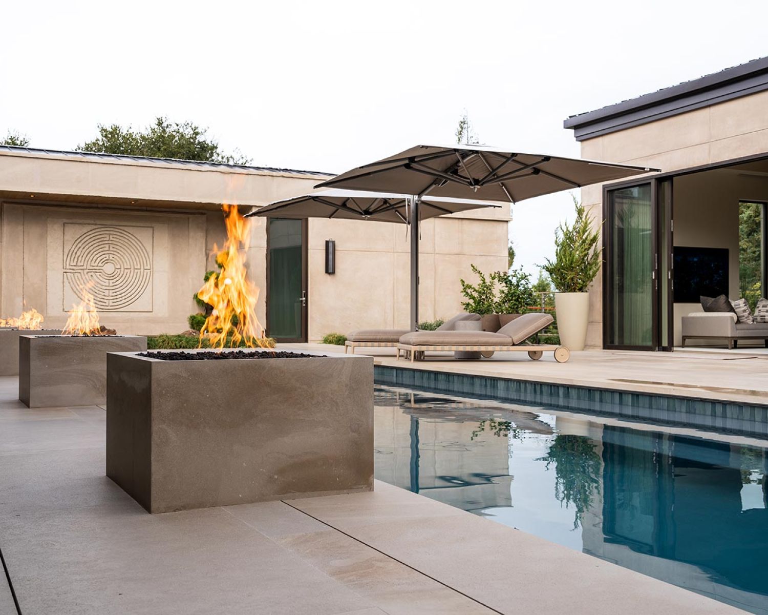 Wide view of modern pool patio with fire features