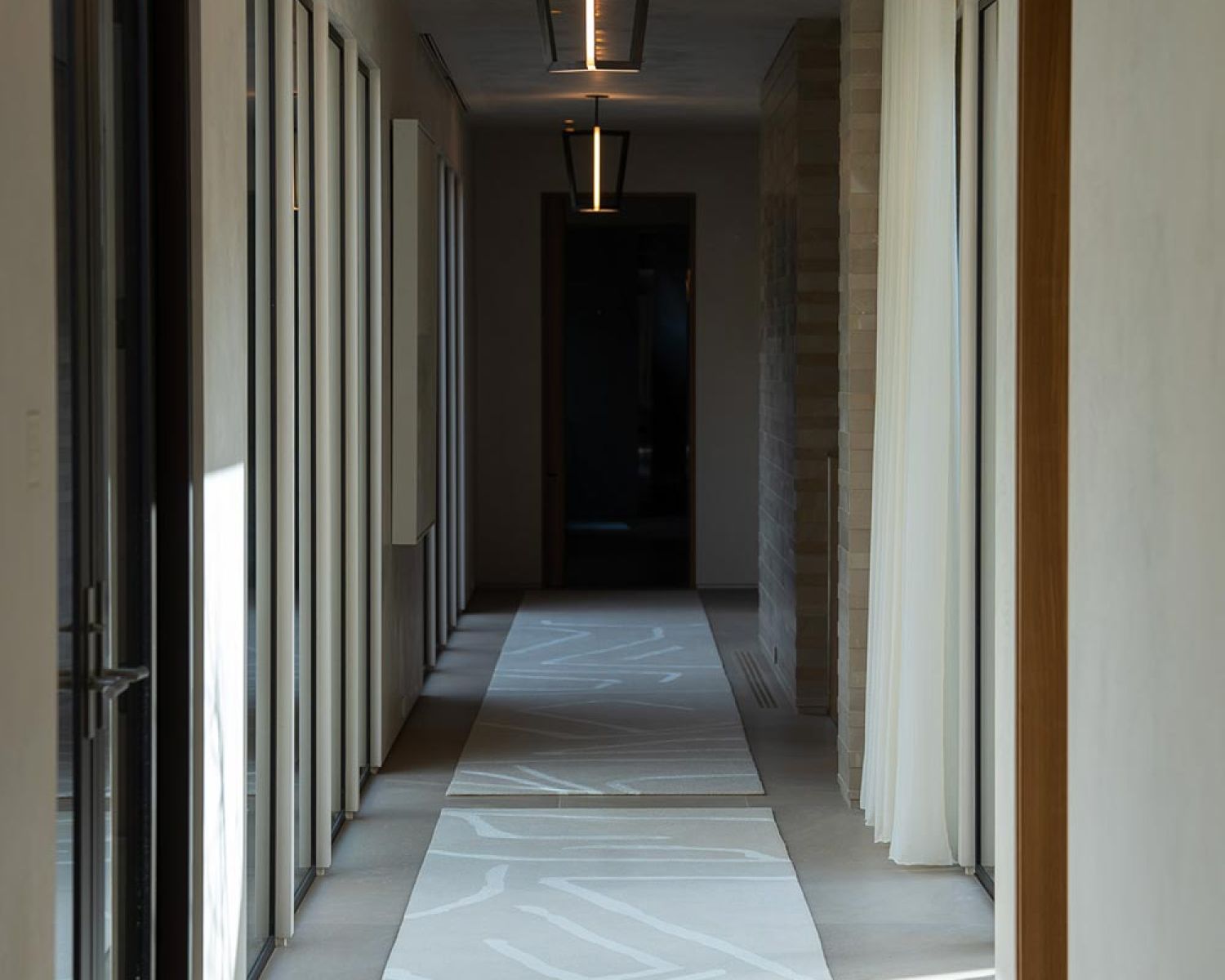 Long hallway with modern pendant lights and patterned rugs