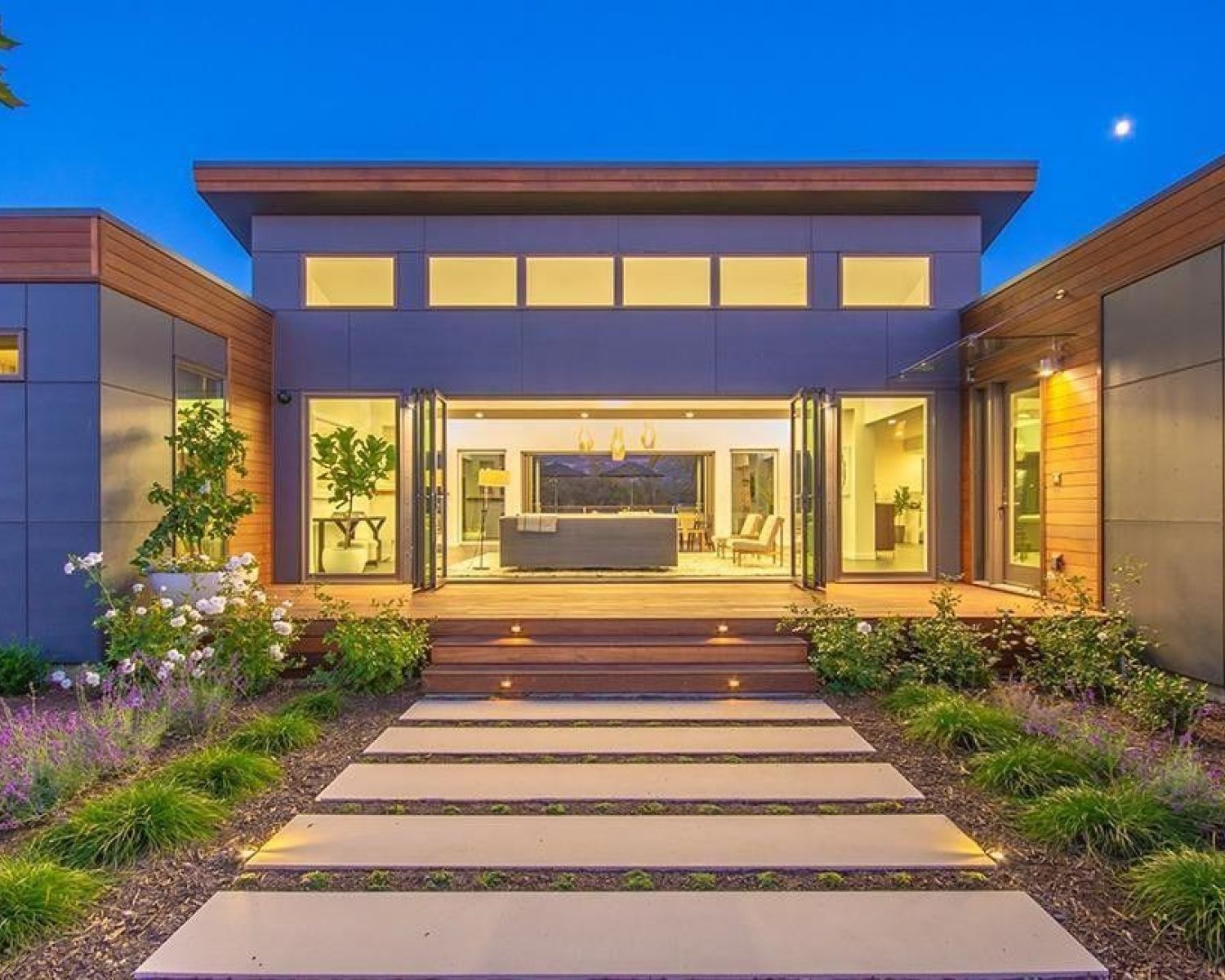 modern home lit up at dusk with glass front
