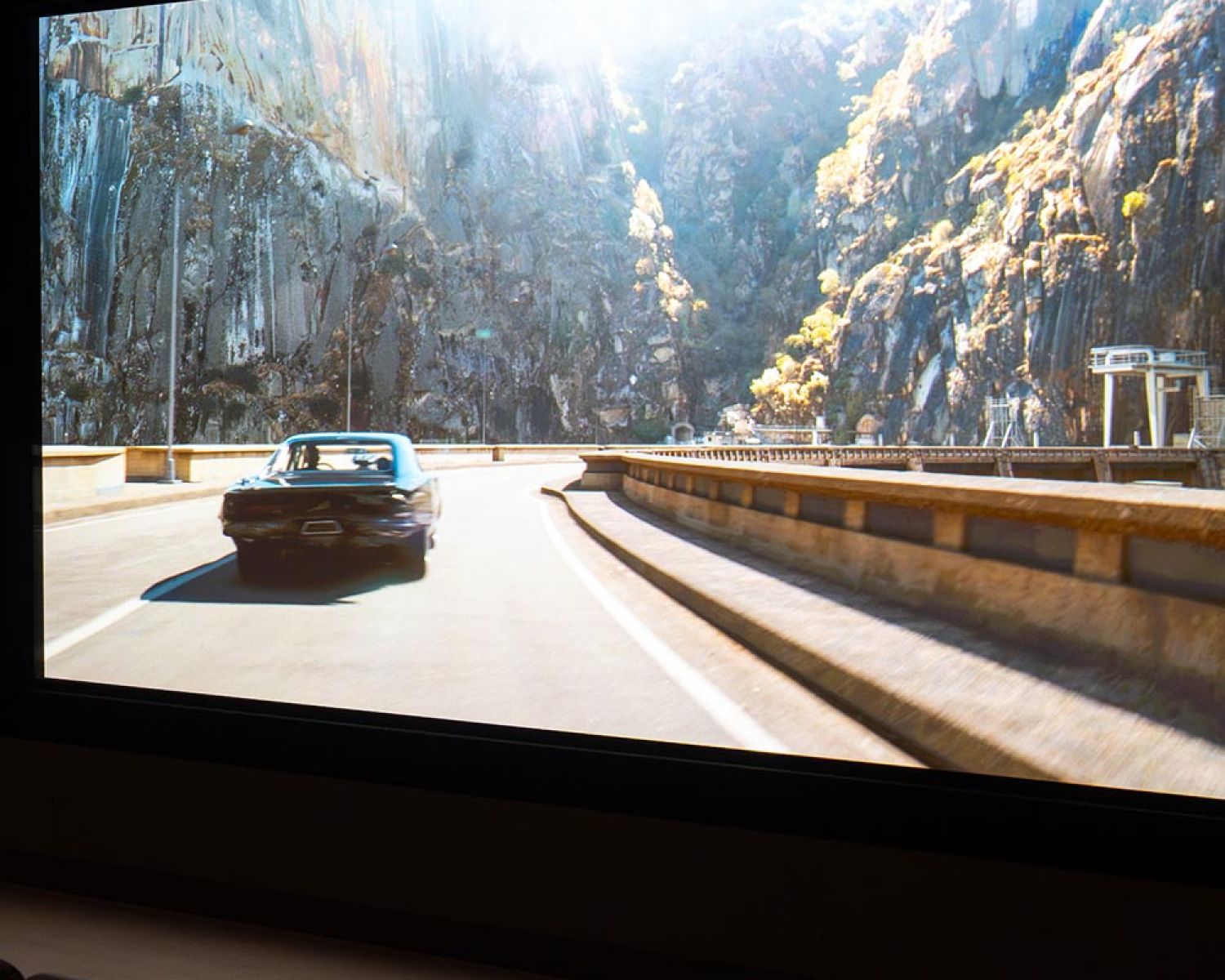 Wide view of home theater screen showing scenic driving scene