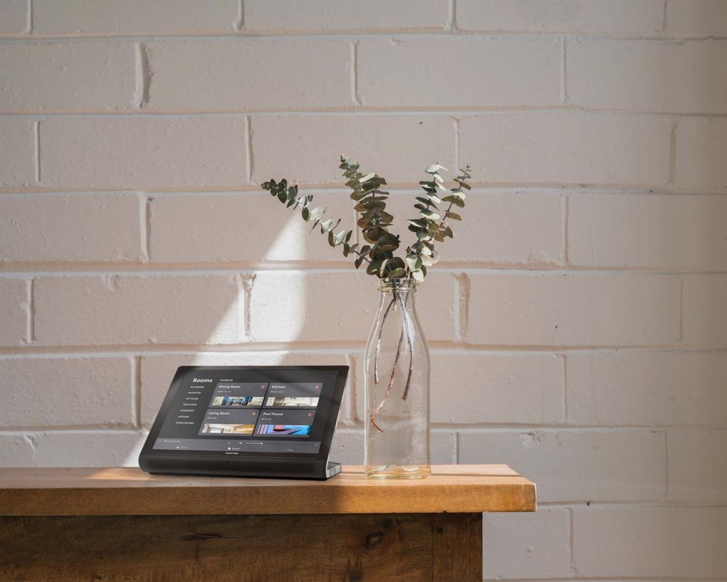 Crestron touch panel on wooden table next to eucalyptus leaves