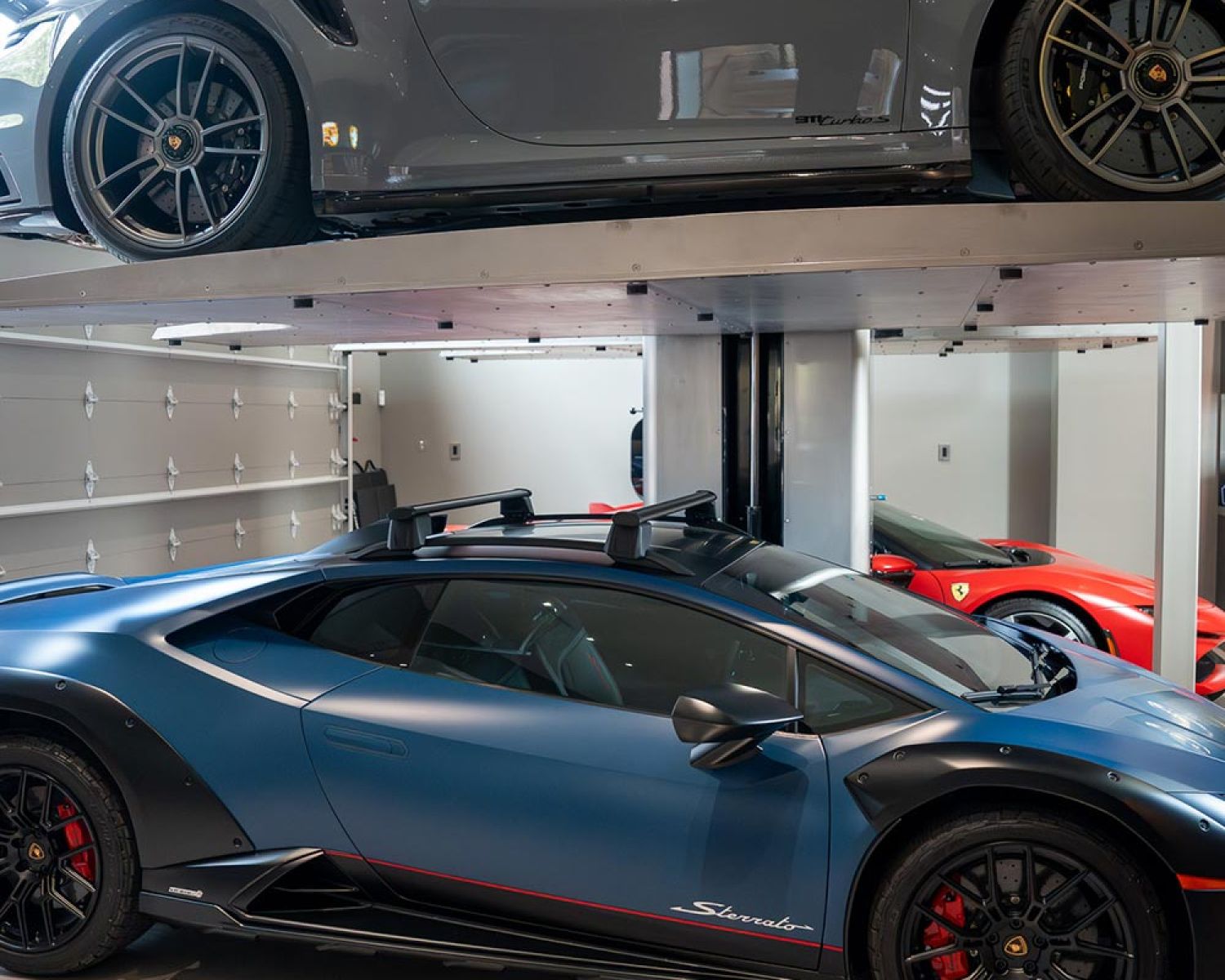Side view of two sports cars stored on stacked garage lifts
