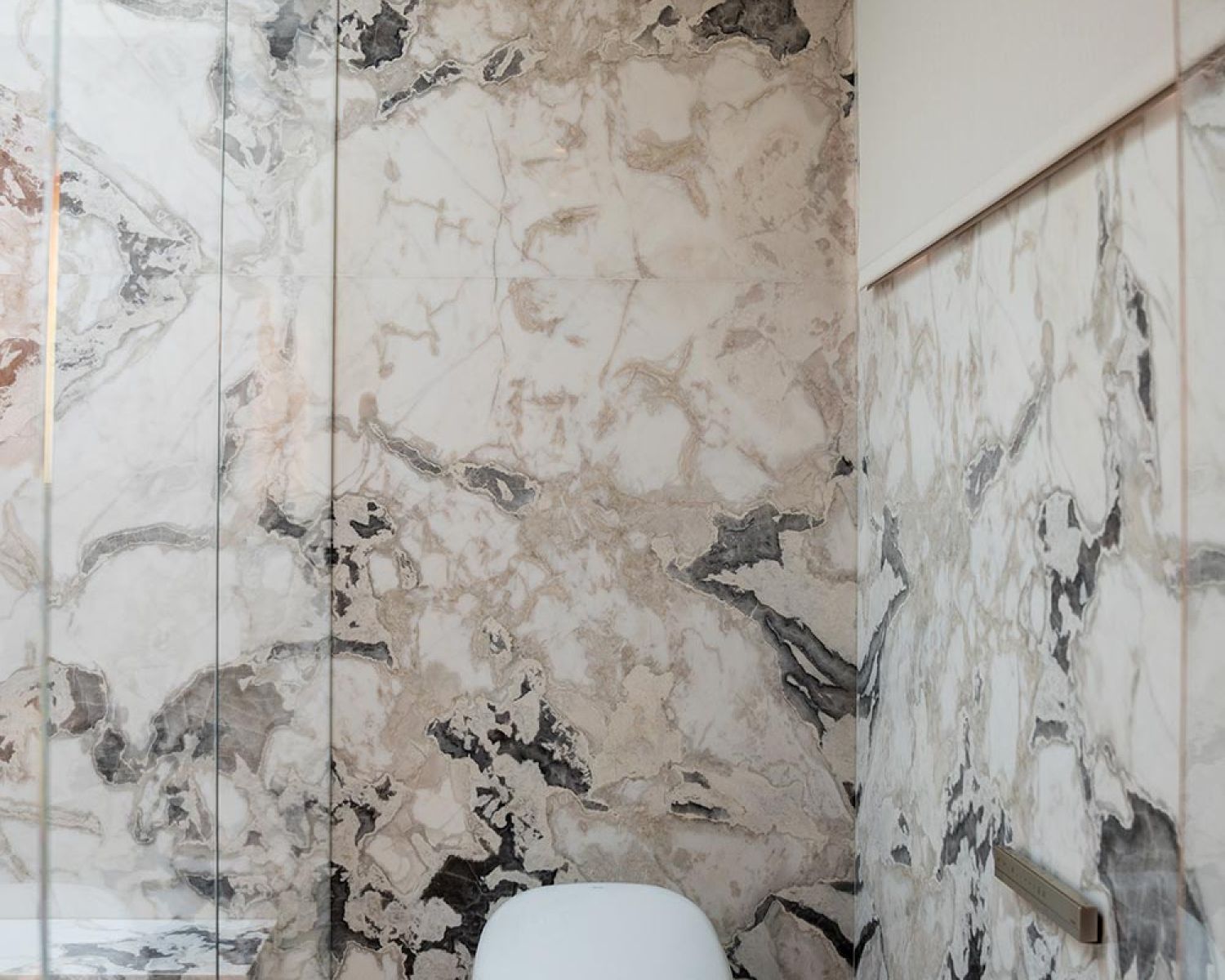 Modern bathroom toilet with marble walls and glass shower