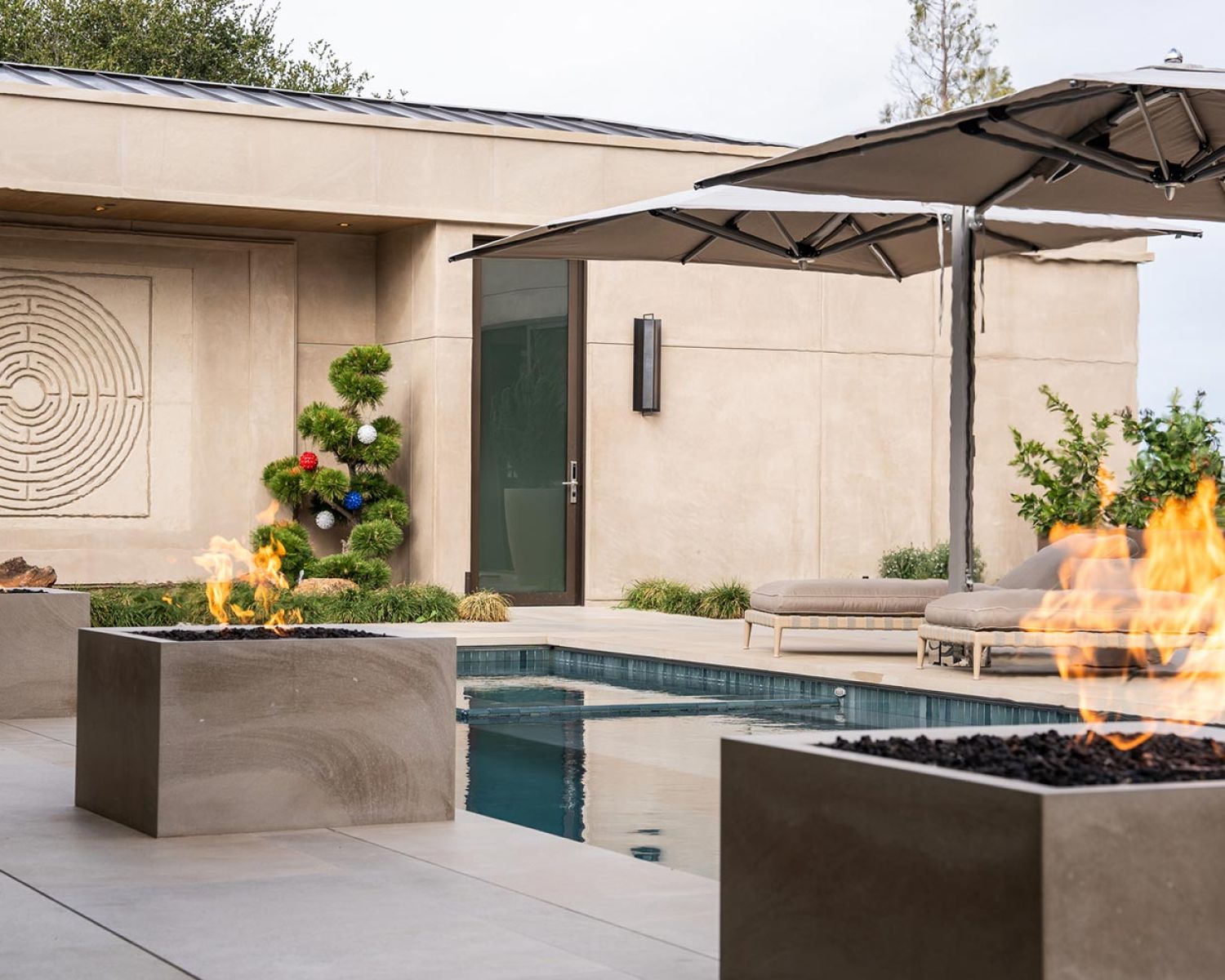 Modern poolside patio with fire features and lounge seating